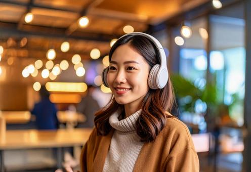 カフェでヘッドフォンをつける女性の写真