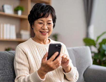 自宅のリビングでスマホを操作する女性 自宅のリビングでスマホを操作する女性の写真