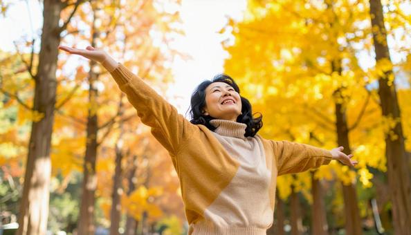 紅葉の中で深呼吸する秋服の日本人女性 紅葉の中で深呼吸する秋服の日本人女性の写真