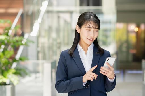スマートフォンを使う若いビジネスウーマン スマートフォンを使う若いビジネスウーマン スマートフォン,スマホ,携帯電話の写真素材