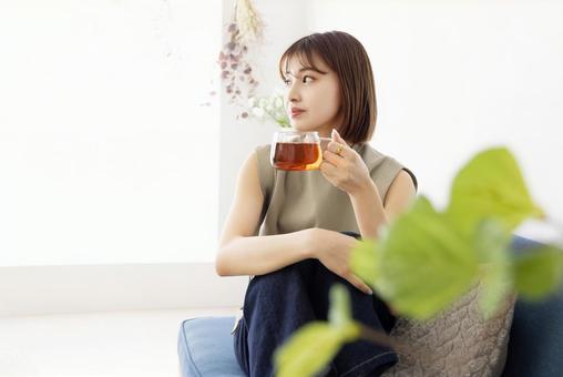 ソファーに座って紅茶を飲む女性 ソファーに座って紅茶を飲む女性の写真