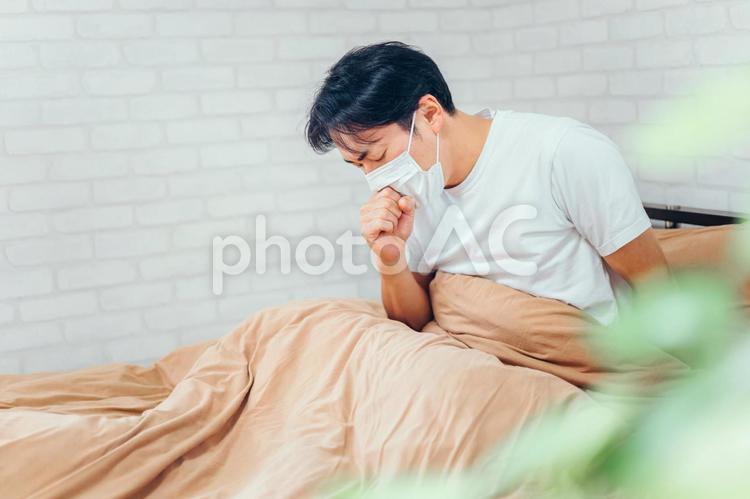 ベッドで休む体調不良の男性（咳） 風邪,咳,せきの写真素材