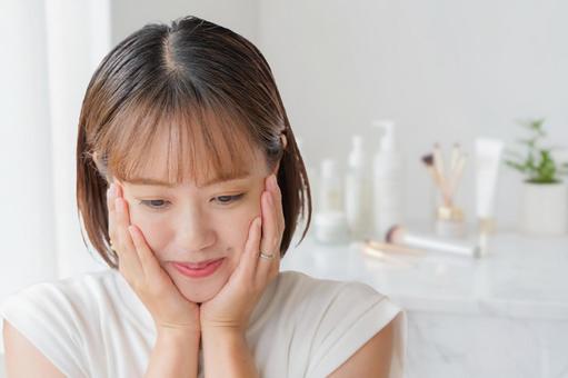 頬を押さえる女性と化粧品 女性,美容,スキンケアの写真素材
