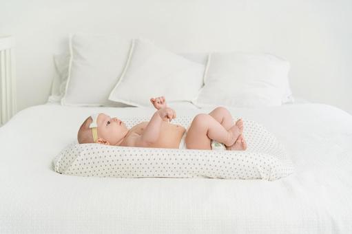 仰向けでベッドに寝かされている赤ちゃん 仰向けでベッドに寝かされている赤ちゃんの写真
