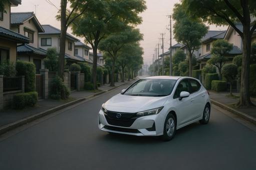 夕方の住宅街を走行する電気自動車(白) 夕方の住宅街を走行する電気自動車(白)の写真