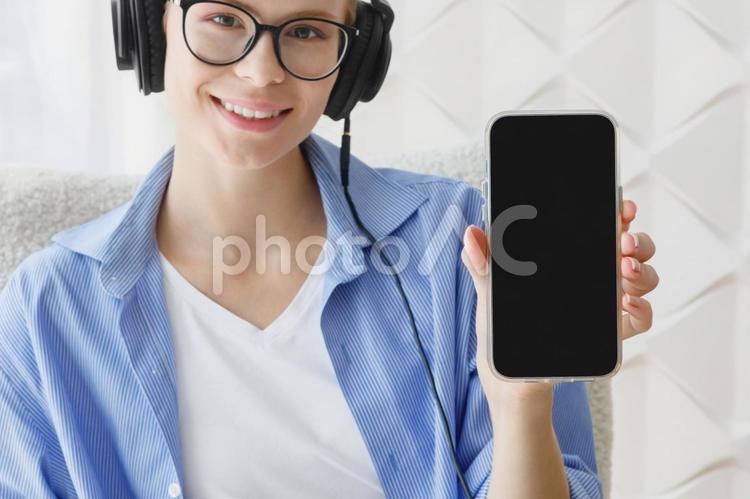 スマホ画面を見せる笑顔の女性 女性,スマートフォン,画面の写真素材