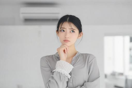 悩む若い女性の考えるポーズの写真