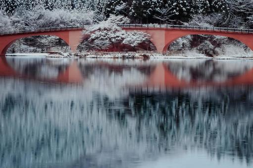 雪化粧した赤い橋と湖のリフレクション 雪化粧した赤い橋と湖のリフレクションの写真