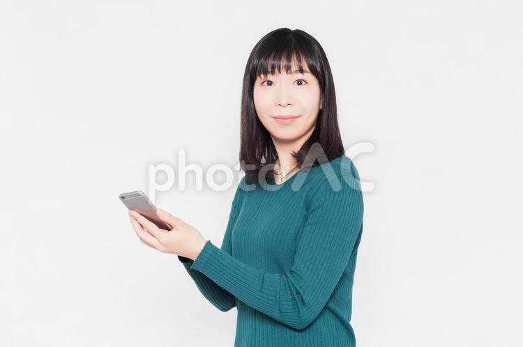 白背景の前でスマホを操作している女性 スマホ,女性,スマートフォンの写真素材