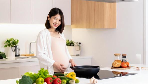 キッチンで料理をする妊婦 キッチンで料理をする妊婦の写真