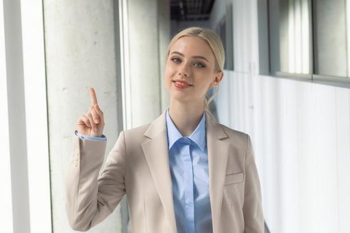 オフィスの通路で人差し指を立てる笑顔のビジネスウーマン ビジネスウーマン,ビジネス,女性の写真素材