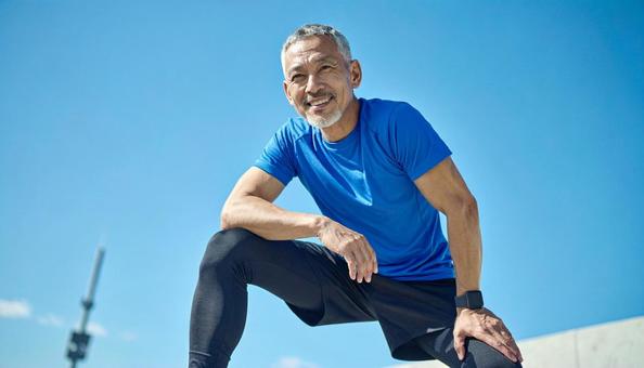 青空の下、ストレッチをするシニア男性 青空の下、ストレッチをするシニア男性の写真