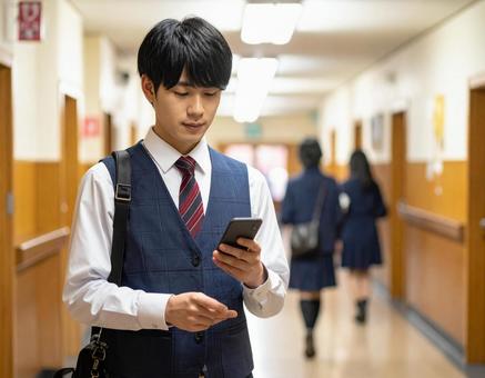 学校の廊下でスマホを操作する男子高校生 学校の廊下でスマホを操作する男子高校生の写真