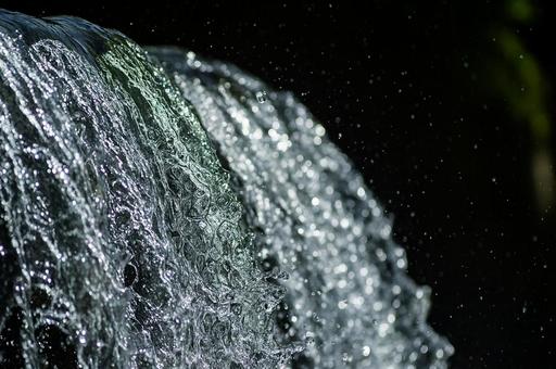 黒背景に浮かび上がる滝の流れの写真