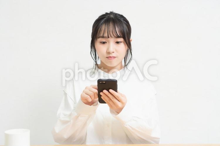 椅子に座ってスマホを使っている若い女性 スマホ,若い,女性の写真素材