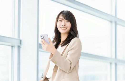 スマホを持つ笑顔の女性・ビジネスウーマン スマホを持つ笑顔の女性・ビジネスウーマンの写真
