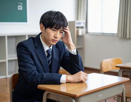 授業中に頭を抱えて悩む男子学生 授業中に頭を抱えて悩む男子学生の写真