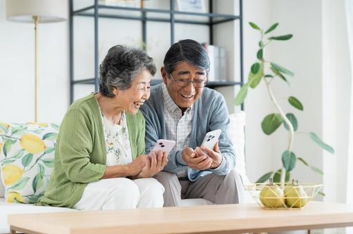 リビングでスマホを見るシニアの夫婦 リビングでスマホを見るシニアの夫婦 シニア,スマートフォン,夫婦の写真素材