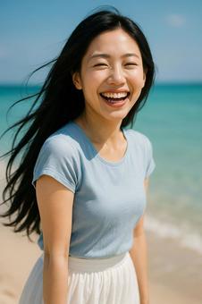 夏の海辺で笑顔を見せる女性青ブラウスの写真