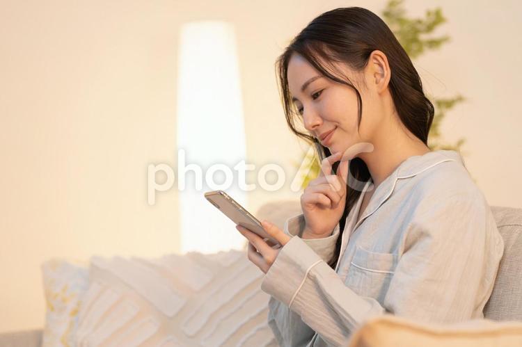 寝室で携帯を見る女性 女性,若い,夜の写真素材