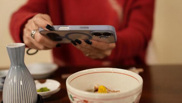 料理の写真を撮る女性 女性,赤いセーター,手の写真素材