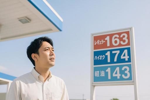ガソリンスタンドで価格表を見上げる男性 ガソリンスタンドで価格表を見上げる男性の写真