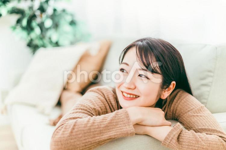 ソファに寝転ぶ女性（リラックス・笑顔） ソファ,女性,笑顔の写真素材