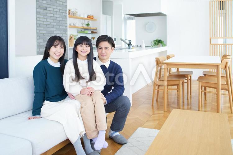 カメラ目線で男性と女性の間に座る女の子 家族,女の子,女性の写真素材