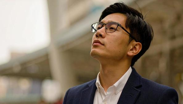 疲れて空を見上げる日本人のサラリーマンの写真