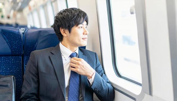電車内で窓を見ながらネクタイを締める男性 電車内で窓を見ながらネクタイを締める男性の写真