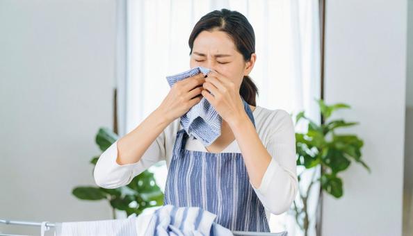 洗濯ものの生乾きの臭いに悩む女性 洗濯ものの生乾きの臭いに悩む女性の写真