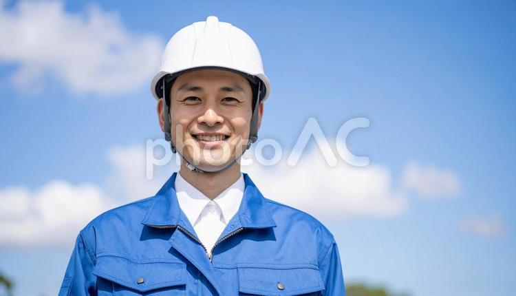 青空の下で笑顔の日本人若い男性建設作業員 作業服,男性,若いの写真素材