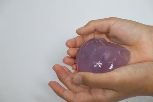 手の中で輝く紫のハート型スライム スライム,ハート,手の写真素材