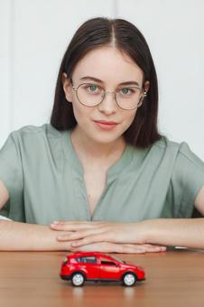 模型の車を前に笑顔を浮かべる女性スタッフ 保険業,事務職,接客業の写真素材