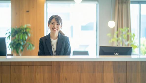 笑顔で対応する女性の受付嬢 笑顔で対応する女性の受付嬢の写真