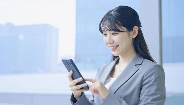 スマホを確認するビジネス女性の写真