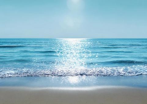 太陽が輝く青い海と砂浜の絶景の写真