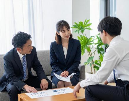 応接室でお客様に資料を説明する上司と部下の写真