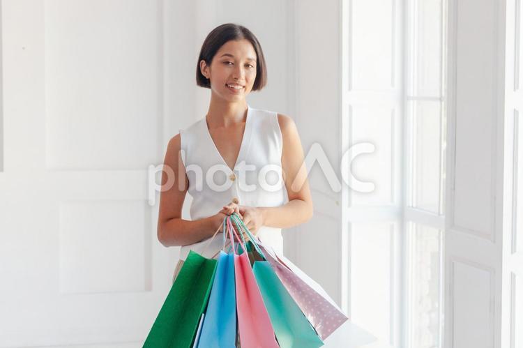 屋内でセールで買った物が入ったたくさんの紙袋を持っている女性 セール,ショップ,女性の写真素材
