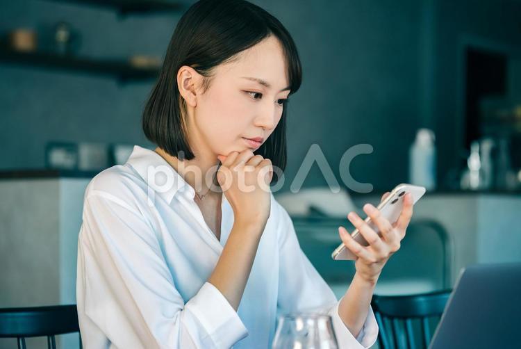 スマホを見て考えるビジネスウーマン 女性,ビジネス,ビジネスウーマンの写真素材