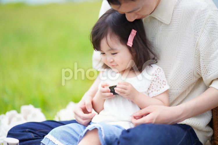 あぐらで座って女の子を座らせる様子 女の子,微笑む,おにぎりの写真素材