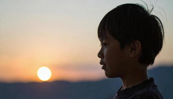 夕焼けの空を見つめる日本人の少年 夕焼けの空を見つめる日本人の少年の写真