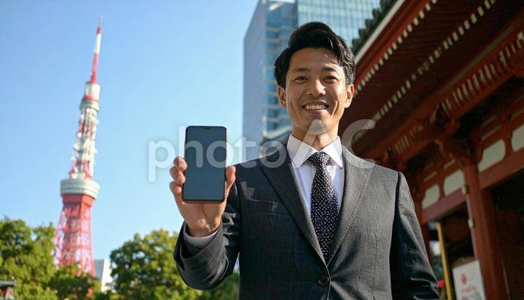 携帯画面を見せて笑うビジネスマン スマートフォン,都市,高層ビルの写真素材