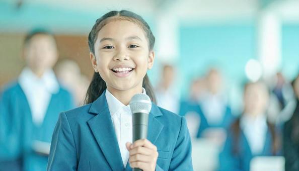 マイクに向かって発表する女子学生 マイクに向かって発表する女子学生の写真