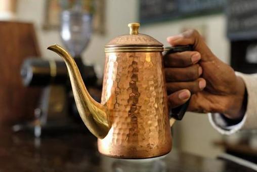 Ethiopian hands with a copper coffee pot Ethiopian hands with a copper coffee pot