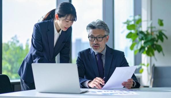 データを見ながら相談する上司と部下 データを見ながら相談する上司と部下の写真