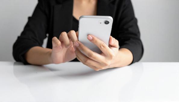 携帯を操作する女性の手元とノートパソコン 携帯を操作する女性の手元とノートパソコンの写真