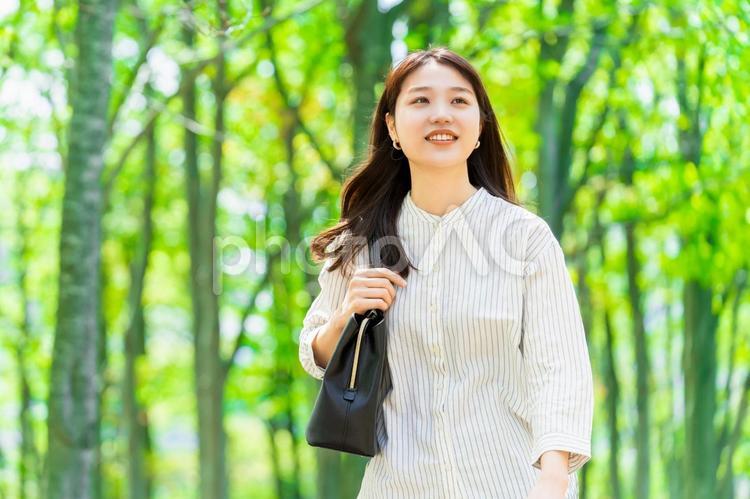 緑の中を歩く笑顔のビジネスウーマン 女性,ビジネス,笑顔の写真素材