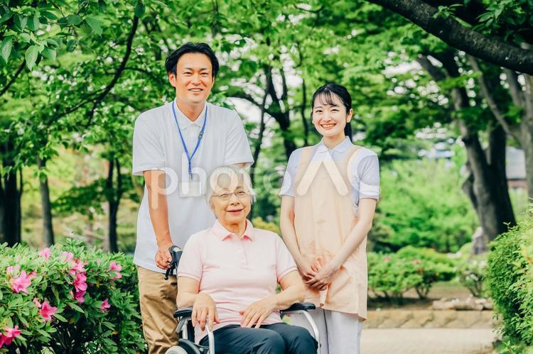 車椅子に乗った高齢者女性と男女スタッフ 介護士,看護師,介護福祉士の写真素材