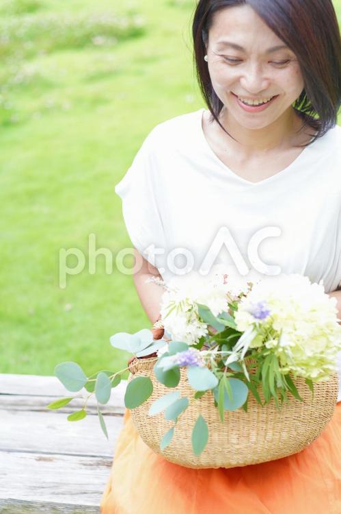 緑の公園で花かごを持った笑顔の中年女性 笑顔,40代,シニアの写真素材